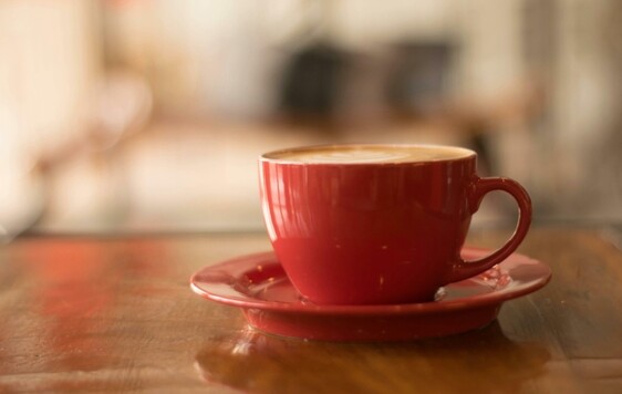 Cup of coffee in an orange mug on wooden counter