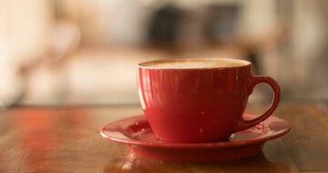 Cup of coffee in an orange mug on wooden counter