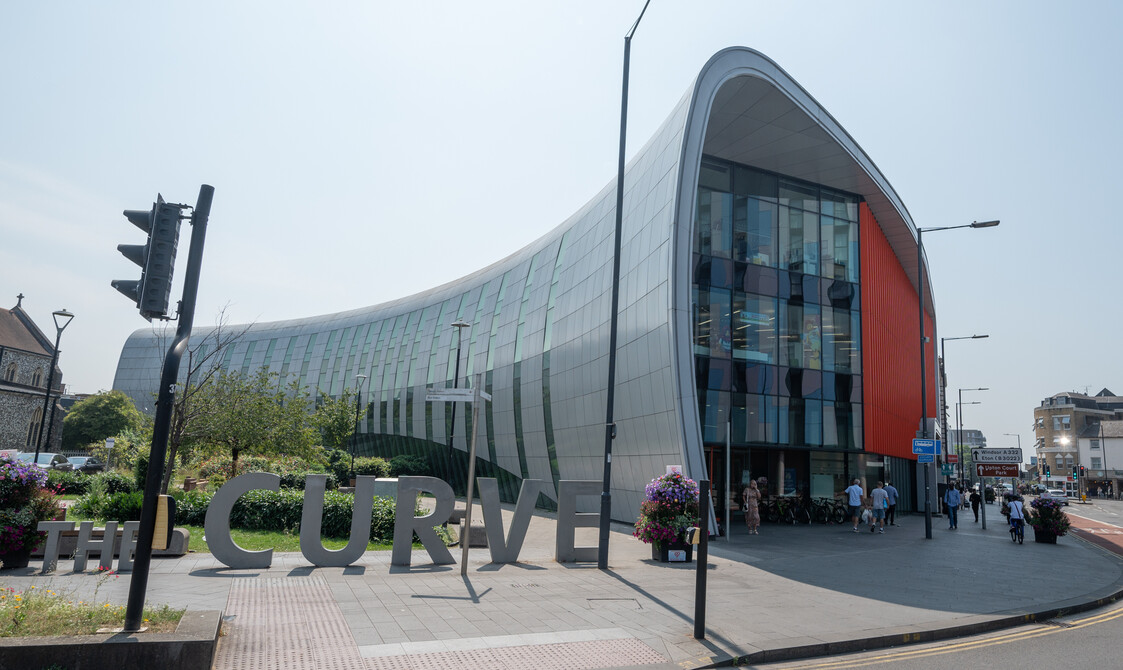External shot of Curve venue, a horn shaped metallic and glass building with the word Curve in 3D metal letters at the front