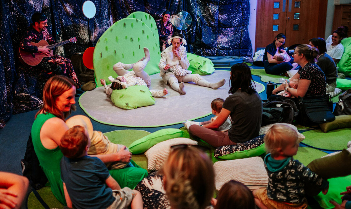 Two actors in sheep costumes performing to a small audience of families
