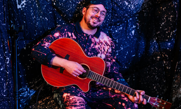 Musician playing guitar with starry backdrop curtain