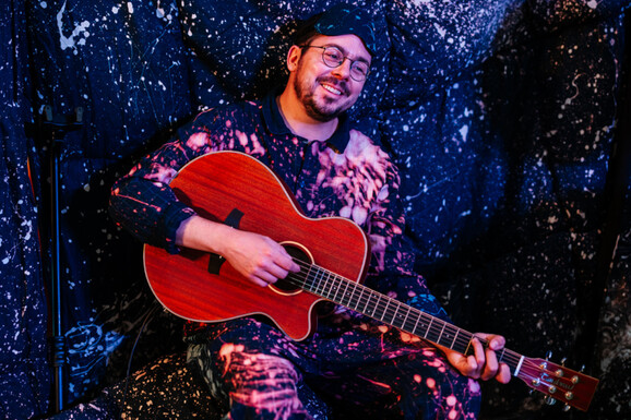 Musician playing guitar with starry backdrop curtain