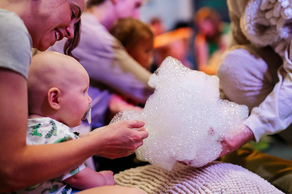 White mother and her baby. Her baby is touching some bubbles.
