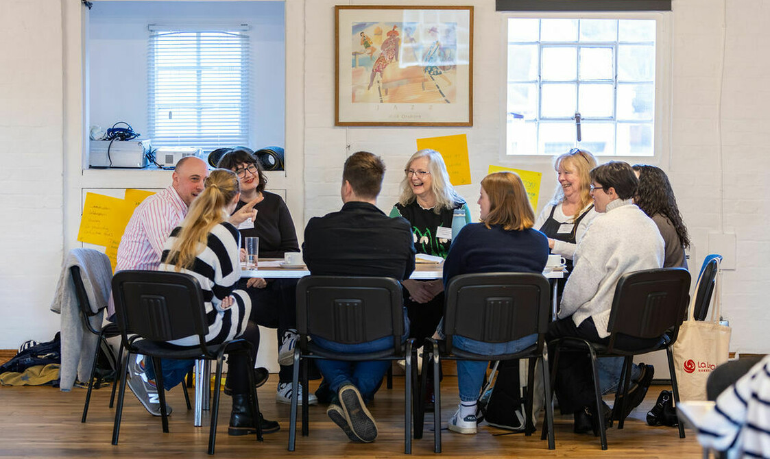 Group of nine people sat around a table chatting, house Network Day 2026