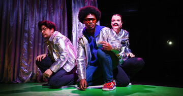 All three performers are crouching with silver jackets on.