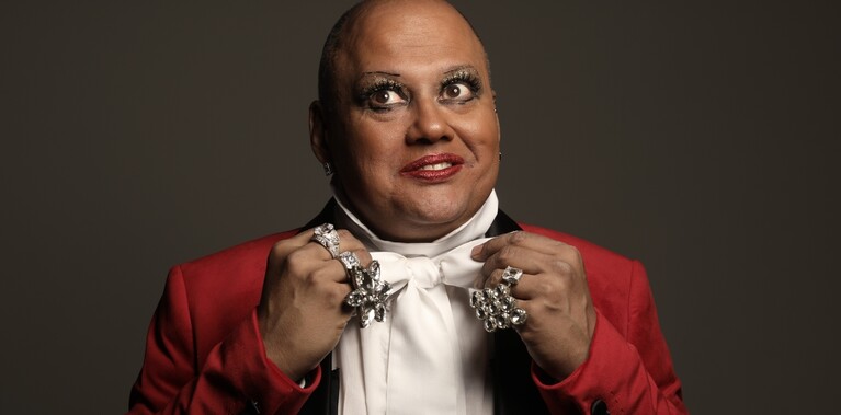 headshot of a Scottish Mauritian man Jonathan in red tux, white shirt and cravat with bling diamond rings