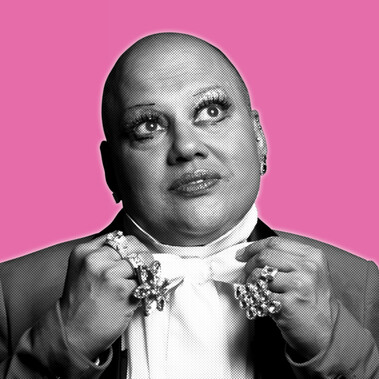Black and white headshot of a man in white dress shirt and jacket, looking up. Wearing big rings on his hands.