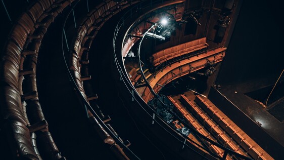 Birdseye view of theatre auditorium seats and stage from the circle, brown leather seating