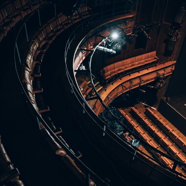 Birdseye view of theatre auditorium seats and stage from the circle, brown leather seating
