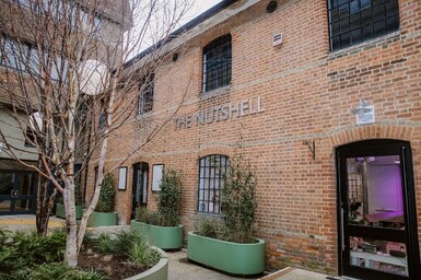 Outside of The Nutshell, Winchester. Brick building with large planters outside.
