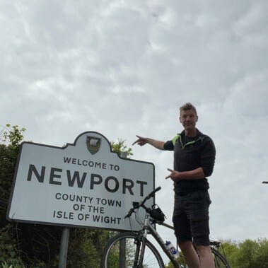 Mark with his bike next to a road sign for Newport, Isle of Wight